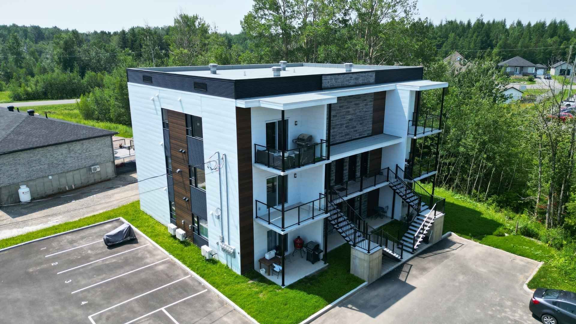 une vue aérienne d'une rangée d'immeubles d'habitation avec des voitures garées devant eux.