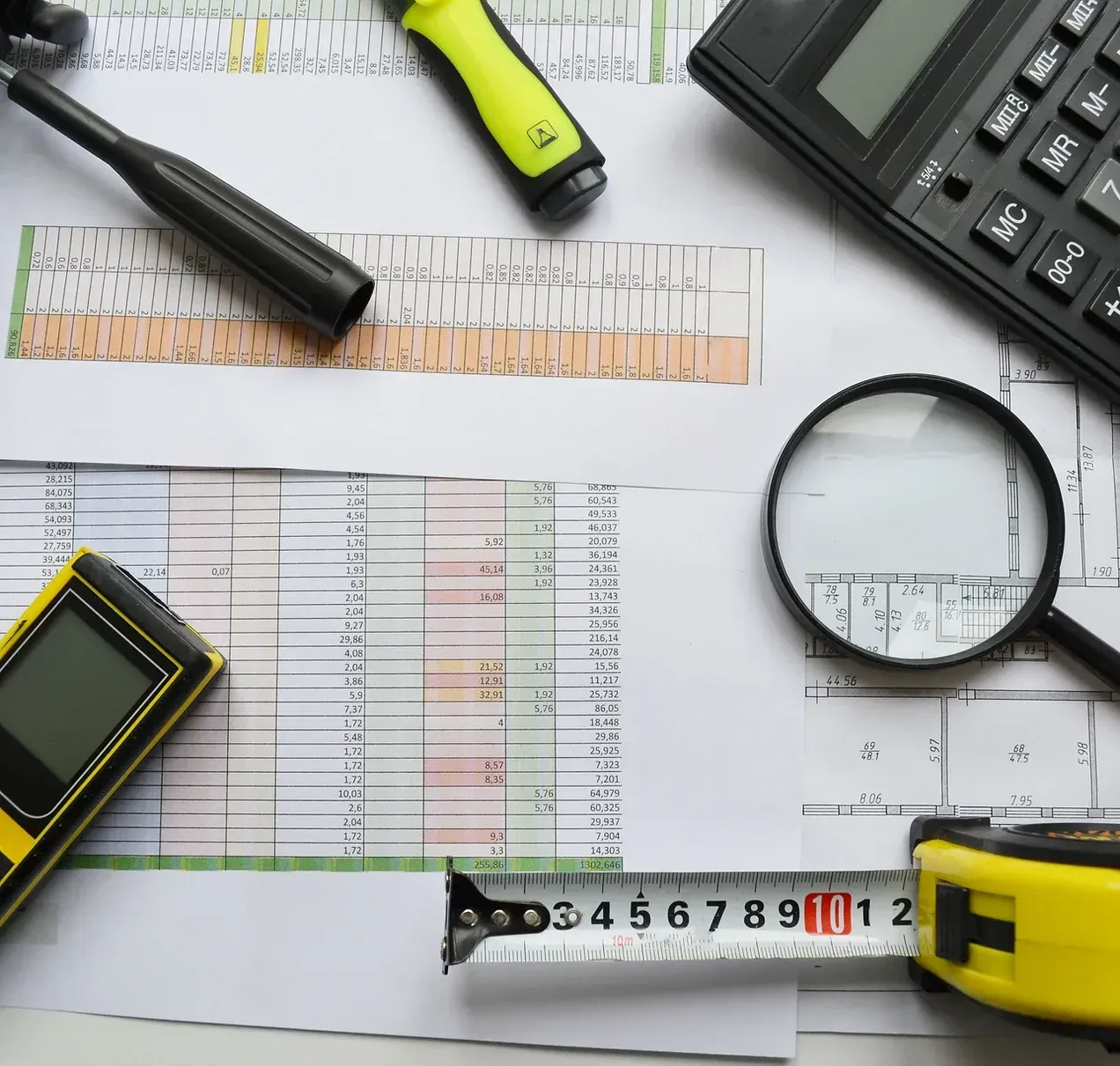 un ruban à mesurer en forme de loupe et une calculatrice au-dessus d'un dessin