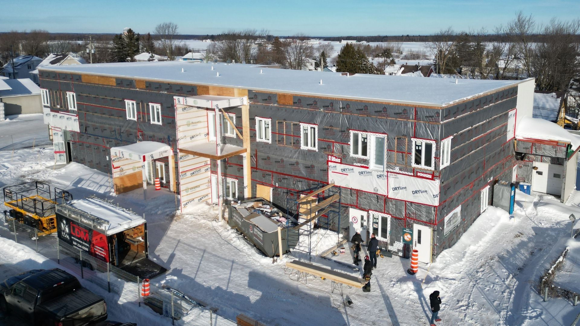 une grande structure en bois est en cours de construction dans un champ de terre.
