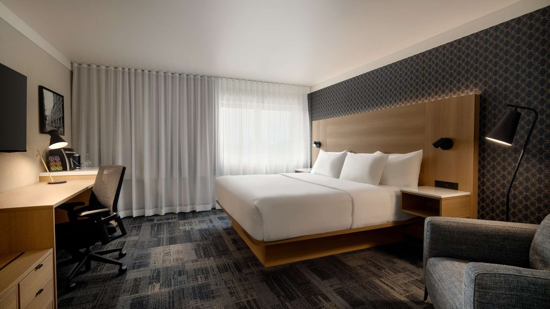 Une chambre d'hôtel avec un bureau, une chaise et une télévision.