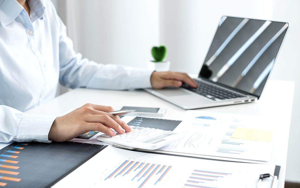 un homme est assis à un bureau et utilise un ordinateur portable et une calculatrice.