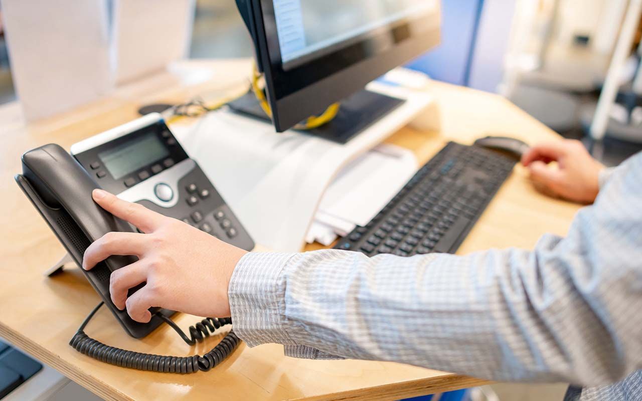 une personne est assise à un bureau et parle au téléphone.