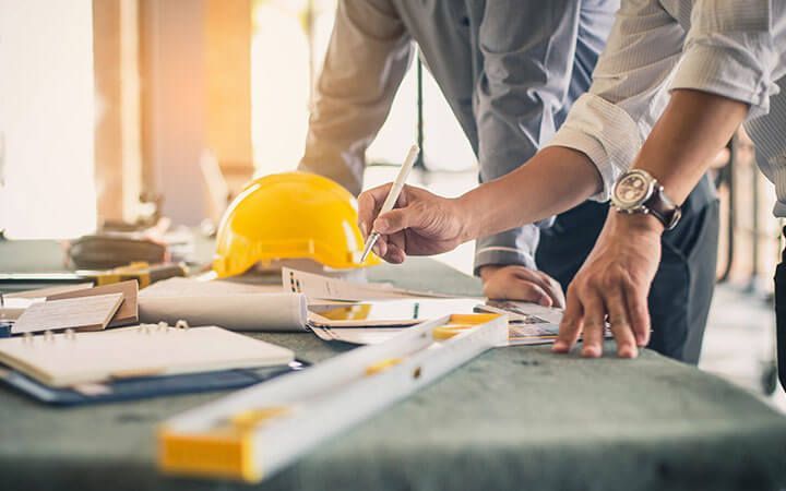 deux hommes travaillent sur un projet de construction à une table.