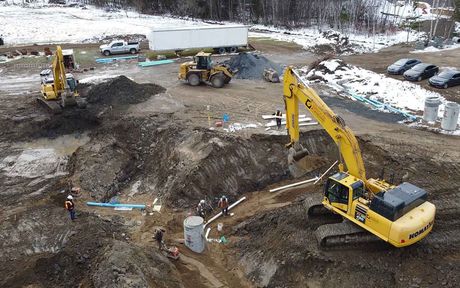 Une vue aérienne d'un chantier de construction avec une excavatrice jaune creusant un trou.