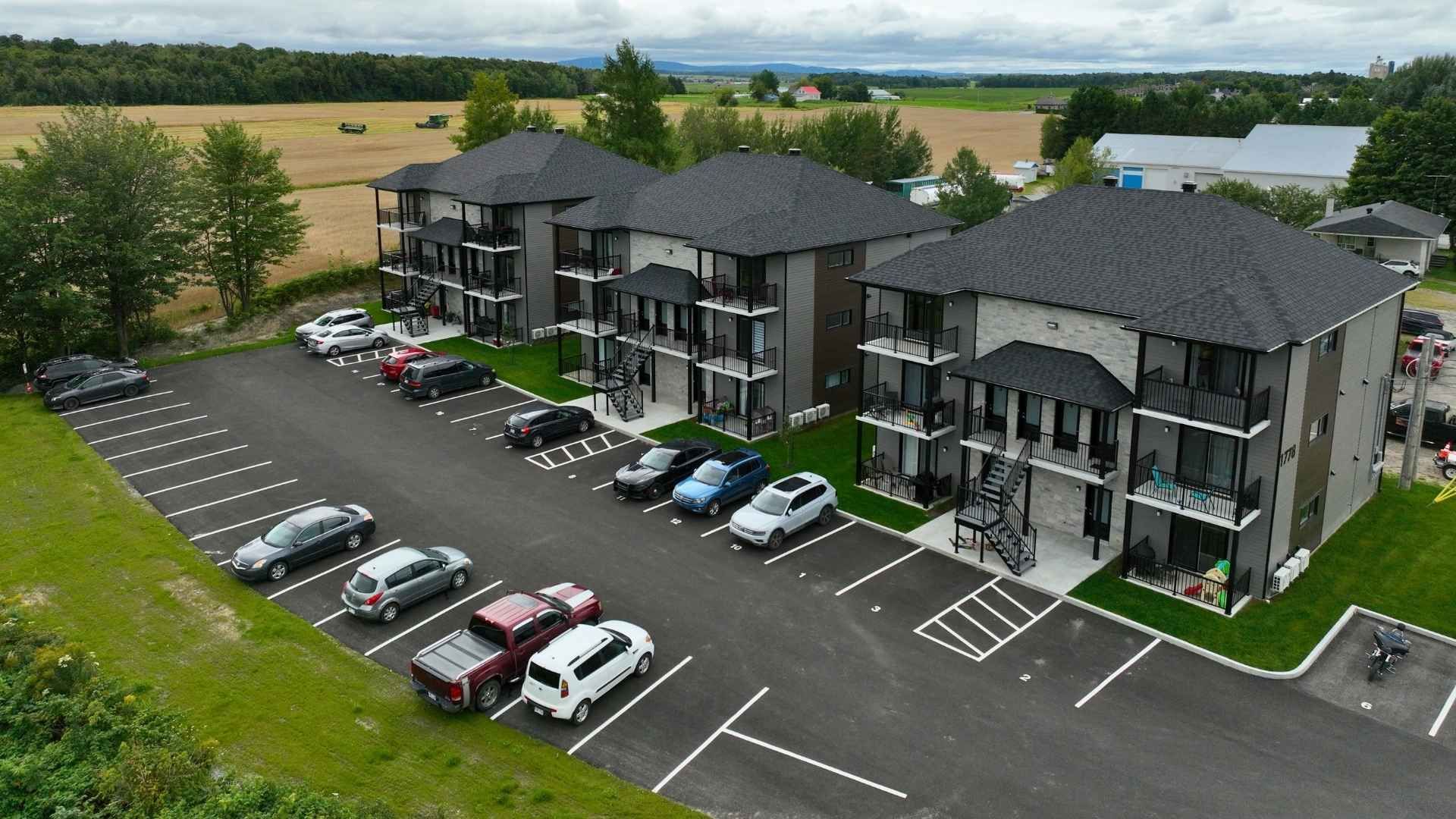 une maison moderne avec de nombreuses fenêtres se trouve au sein d'un champ verdoyant.