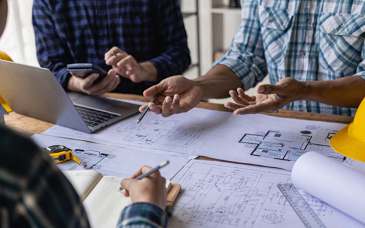 un groupe de personnes est assise autour d'une table et regarde un plan.