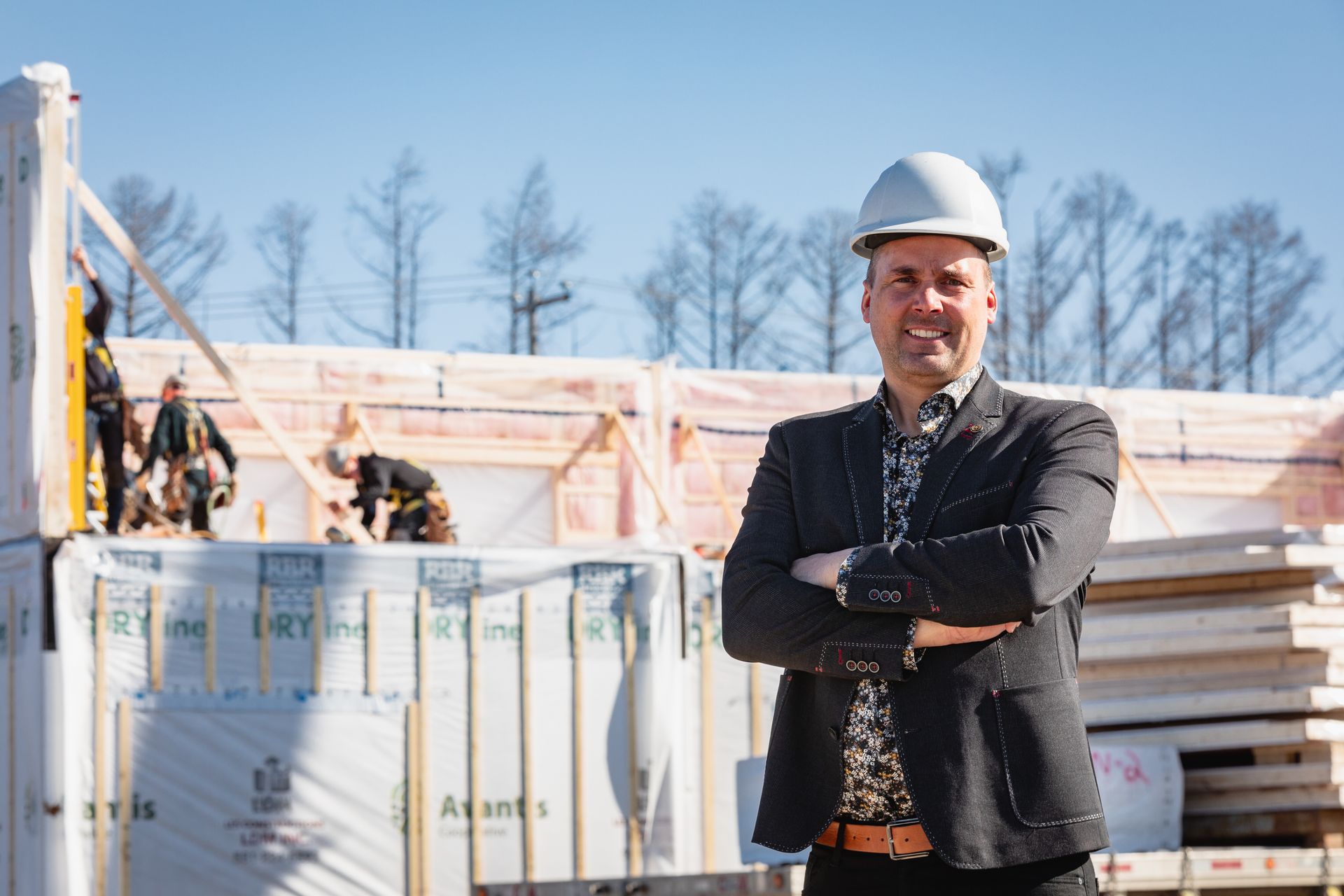 Un homme en costume et casque se tient devant un bâtiment en construction.