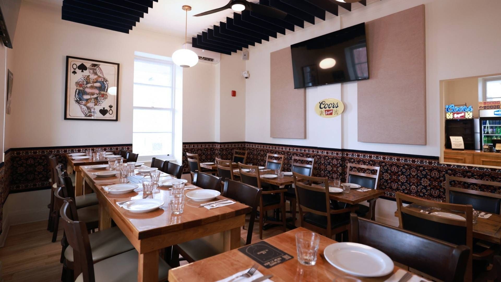 Salle à manger de restaurant avec de longues tables en bois dressées pour le repas.