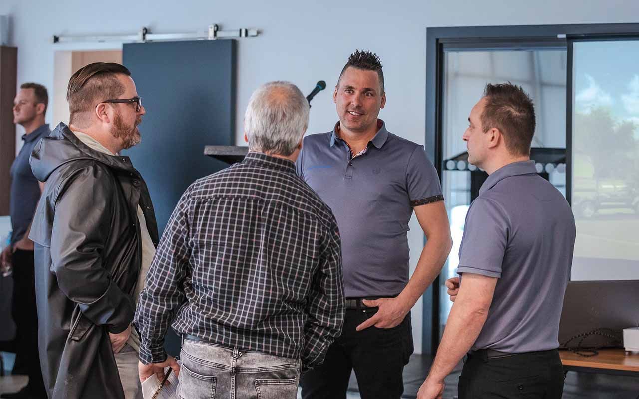 un groupe d'hommes se tiennent dans une pièce et se parlent lors d'une conférence de presse.
