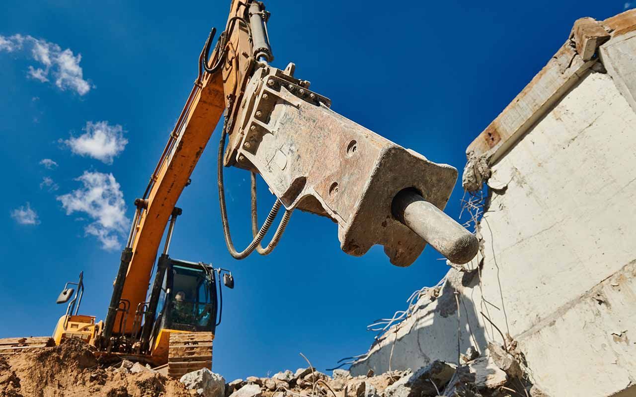 un bulldozer démolit un bâtiment avec un marteau.