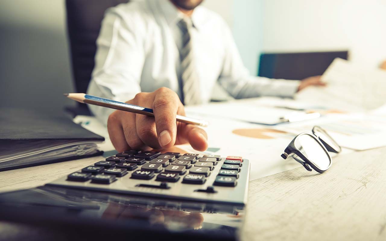 un homme utilise une calculatrice tout en tenant un stylo.