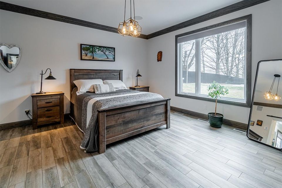 Une chambre avec un lit, une table de nuit, un miroir et une fenêtre.