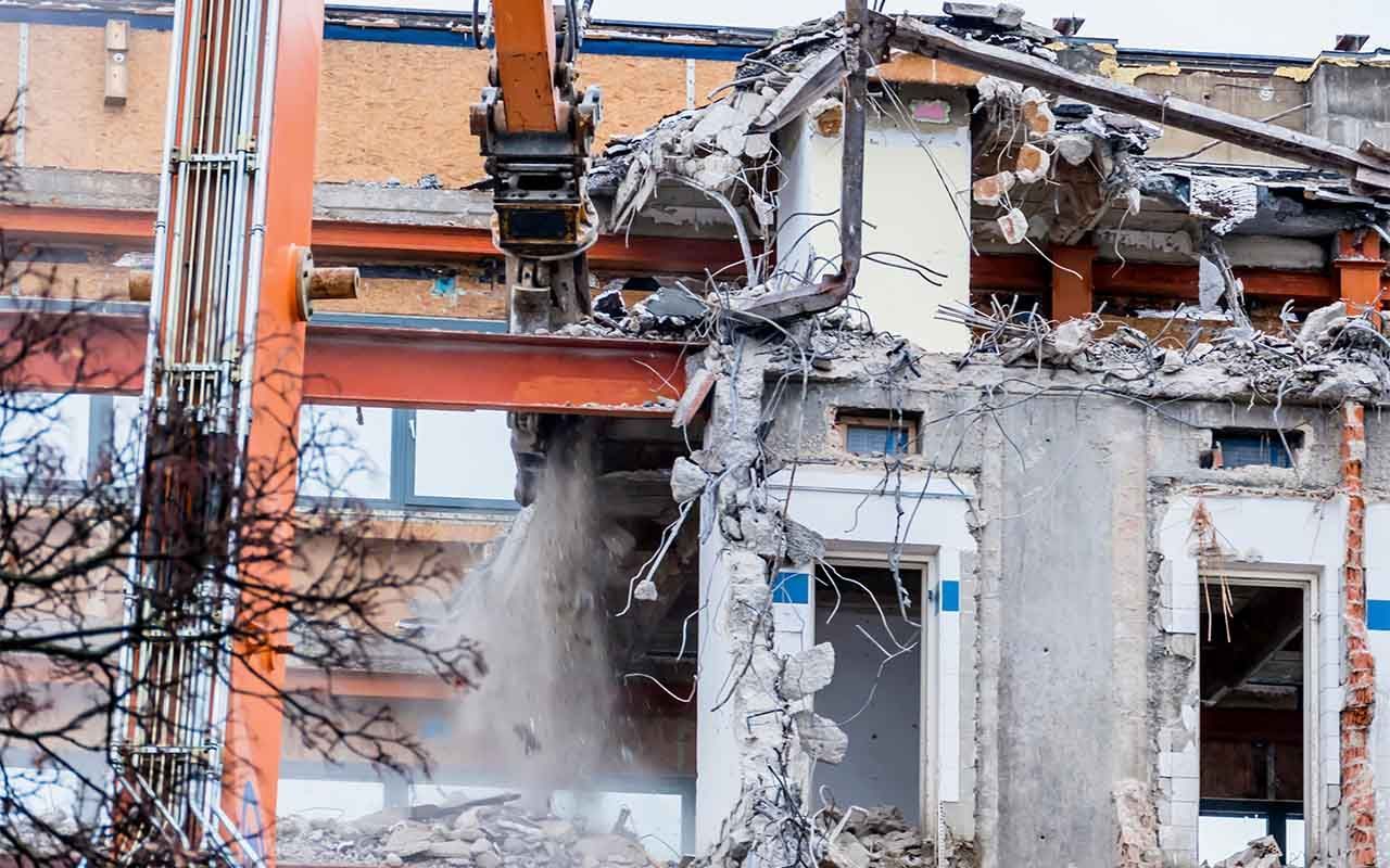 un grand bâtiment est démoli par un bulldozer.