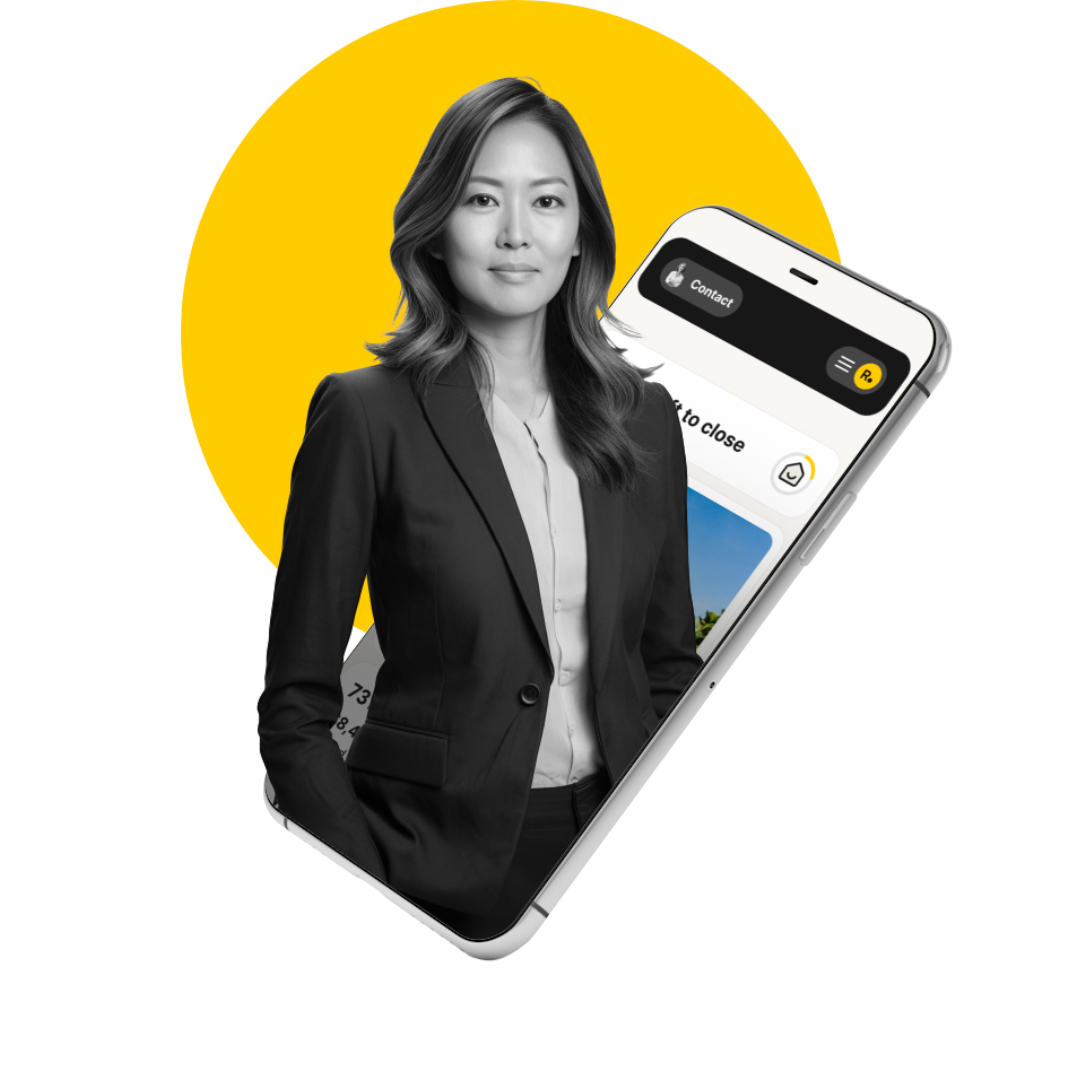 A woman in a suit is standing next to a cell phone.