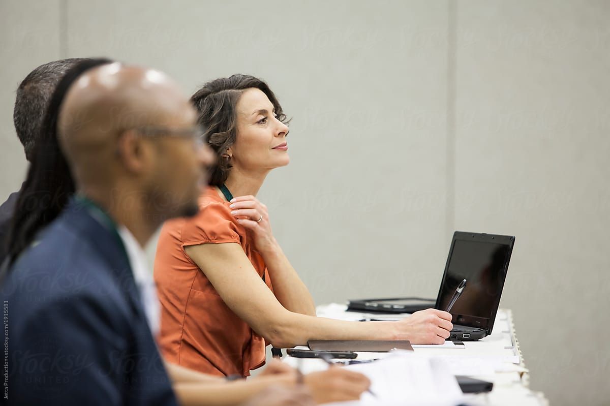 A group of people are sitting at a table with laptops.
