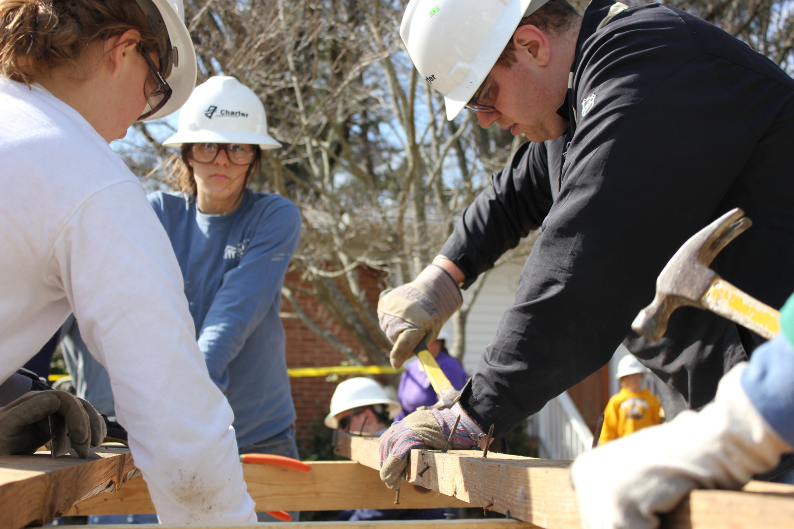 A group of people wearing hard hats are working on a wooden structure.