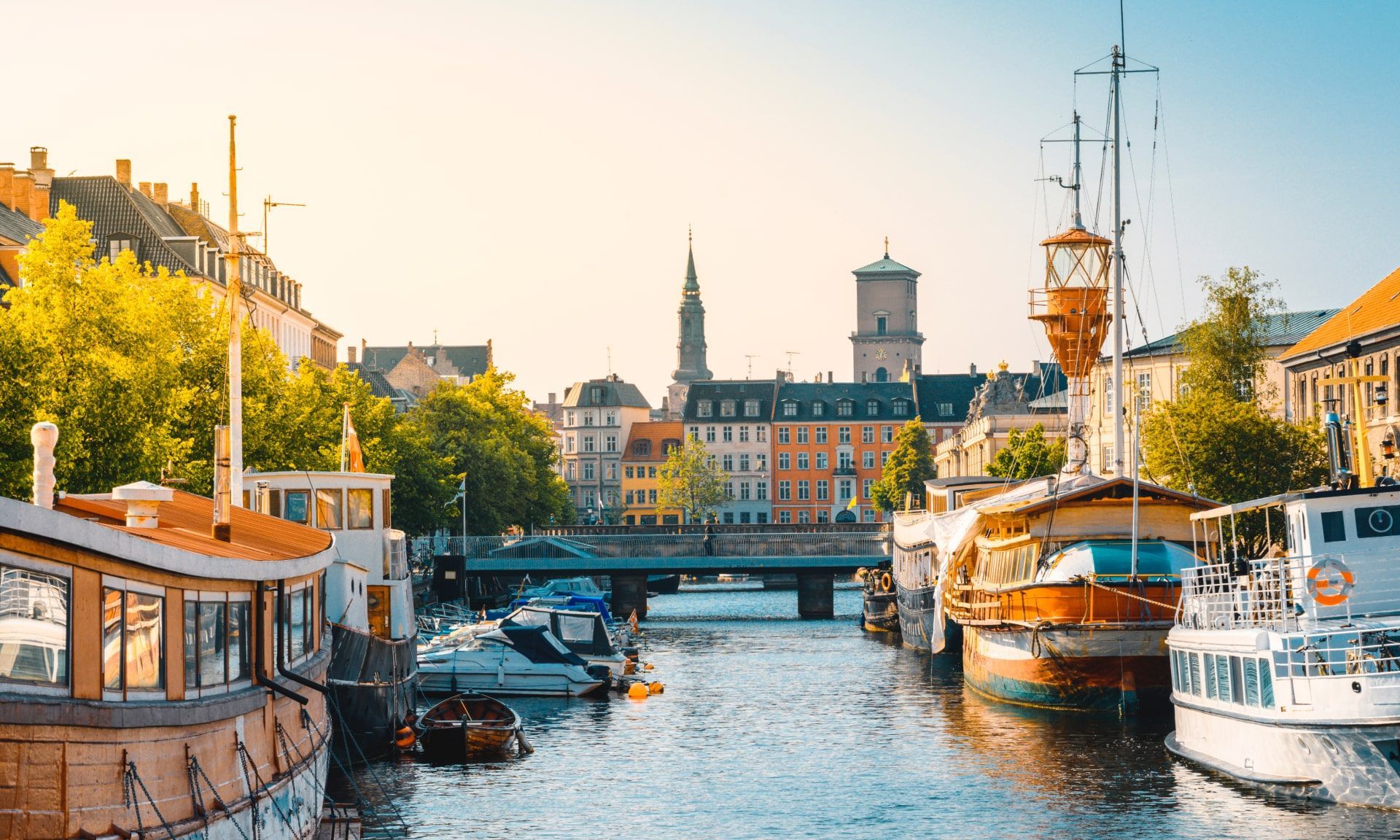 Canal lined with colorful brick buildings and moored boats reflected in calm water at sunset
