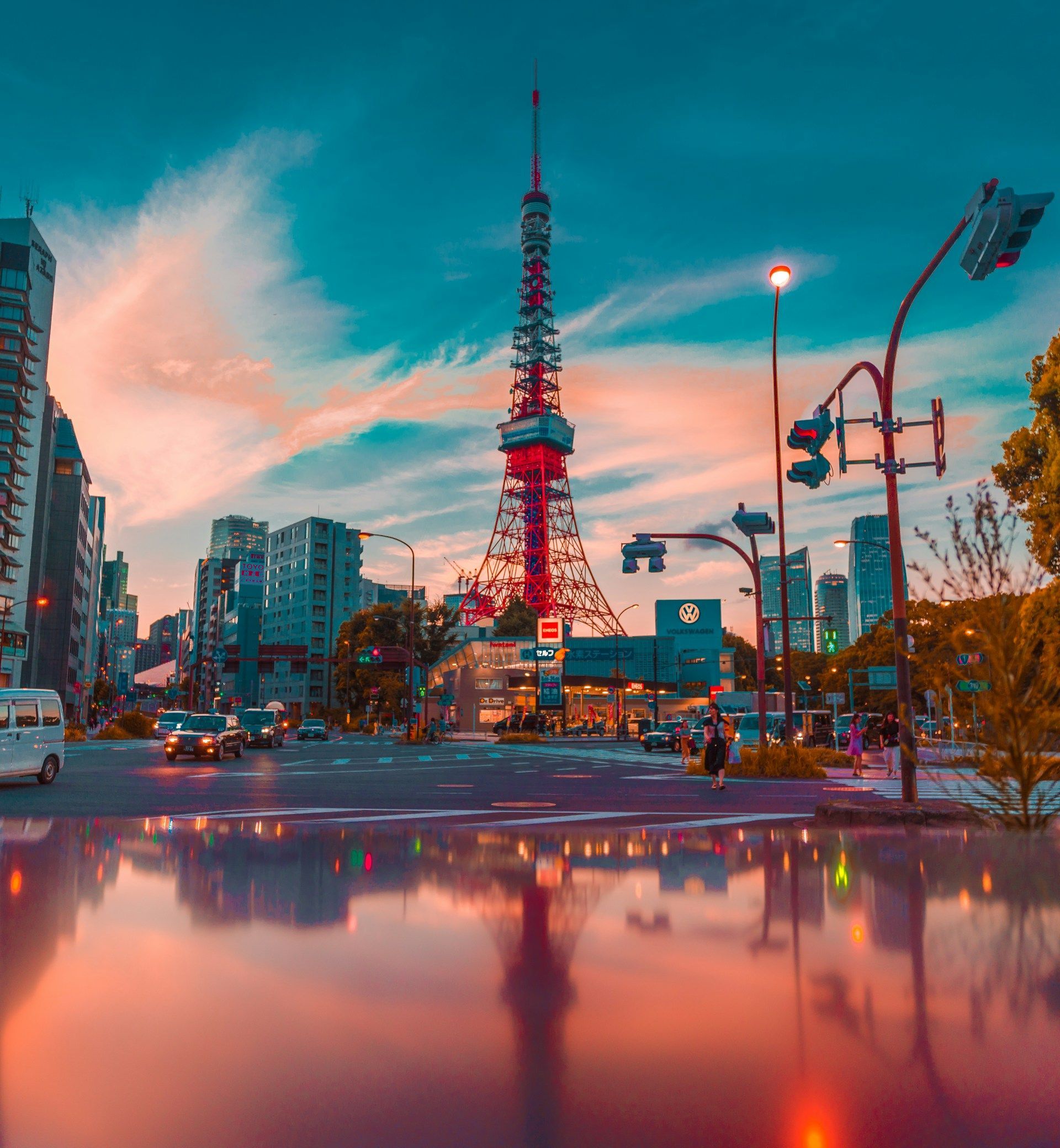 En bygate med et tårn i bakgrunnen og en refleksjon av tårnet i vannet.