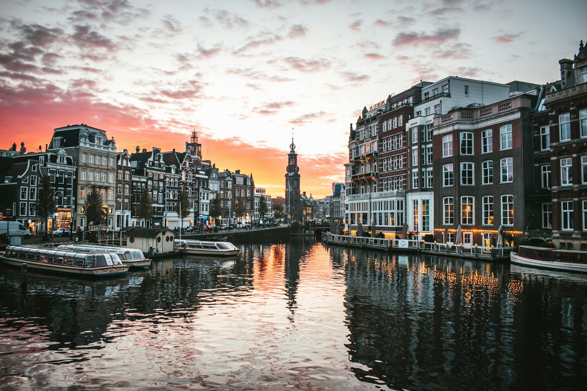 En solnedgang over en kanal med båter og bygninger i bakgrunnen