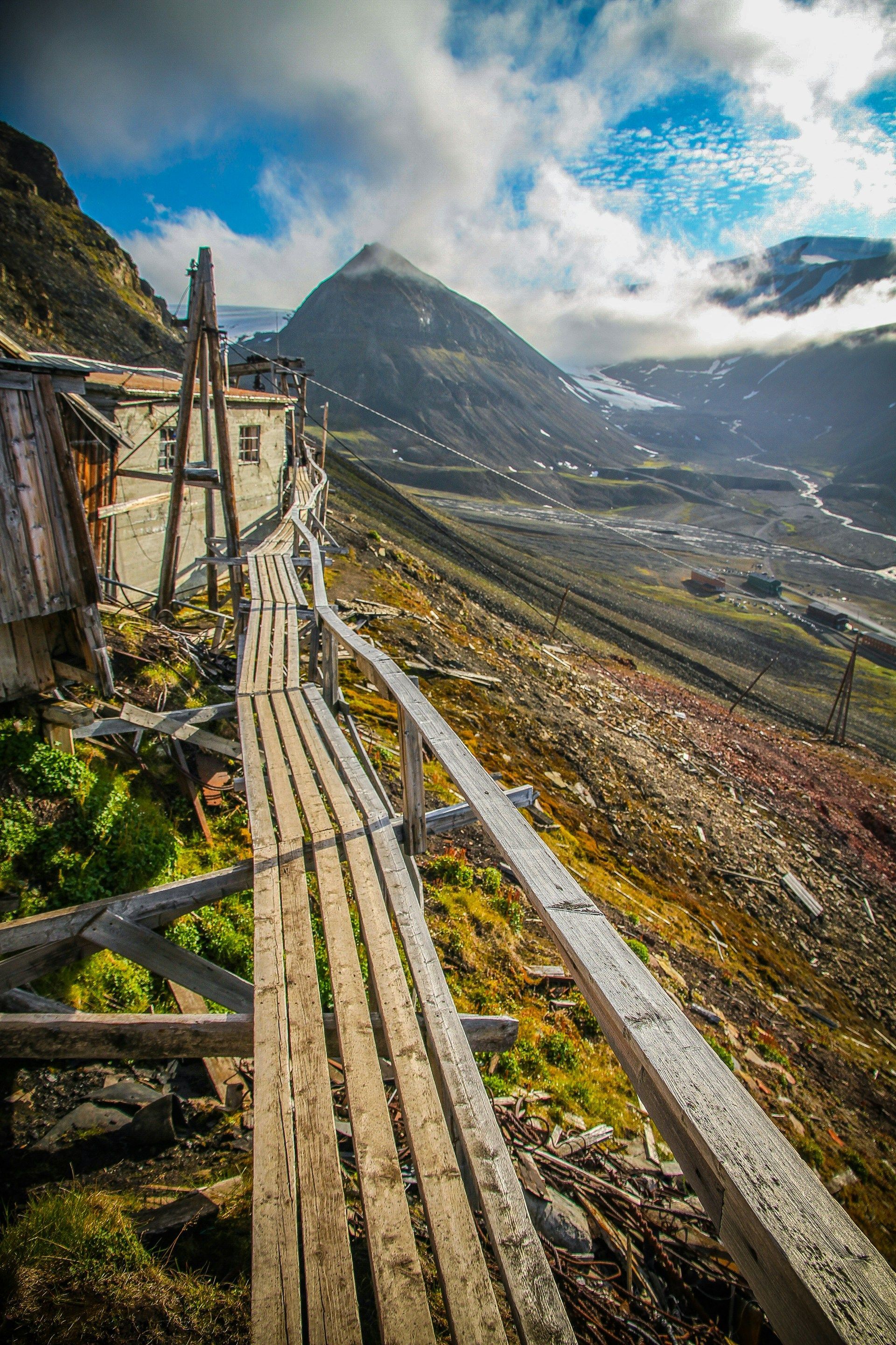 En gangvei i tre som fører til en bygning i fjellet.