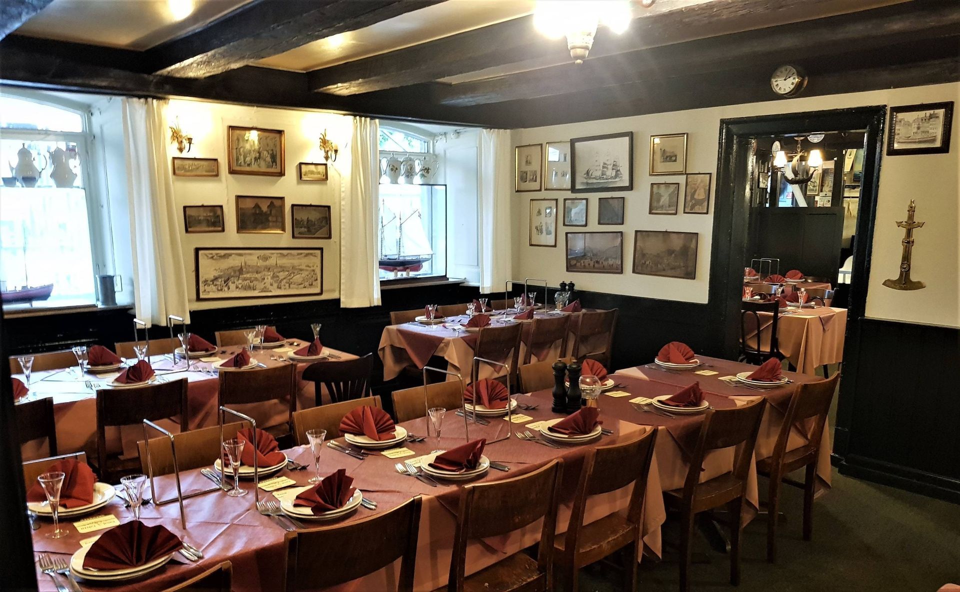 Rustic café interior with wooden beams, round tables, chairs, and sunlight through large windows