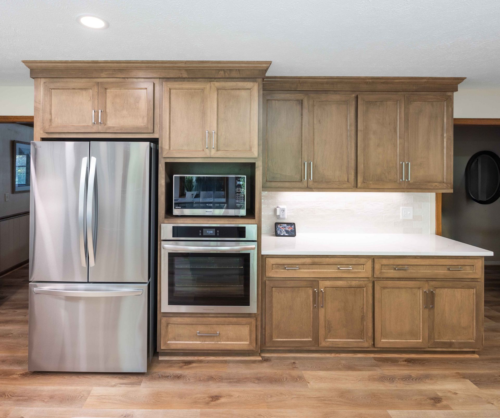 Wooden kitchen with stainless steel refrigerator, built-in oven and microwave, and white countertop