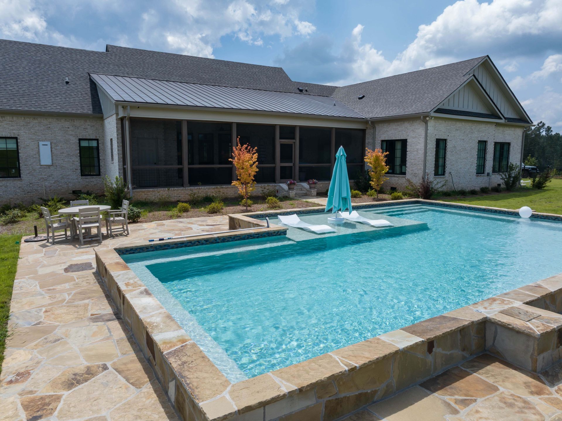 Backyard patio with a rectangular swimming pool beside a modern house and outdoor seating area
