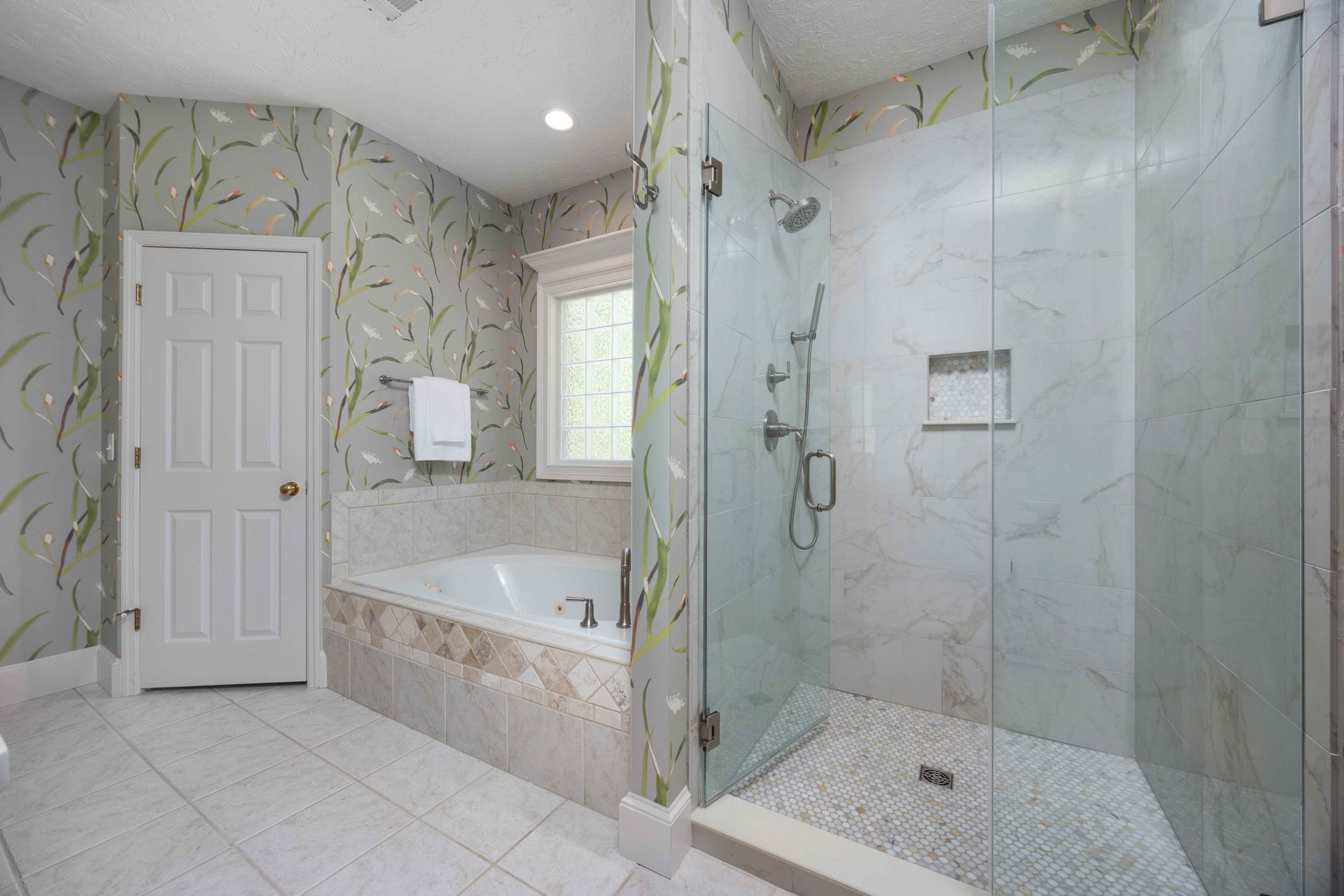 Luxury bathroom with bathtub, glass shower, white tile, and marble walls and floor
