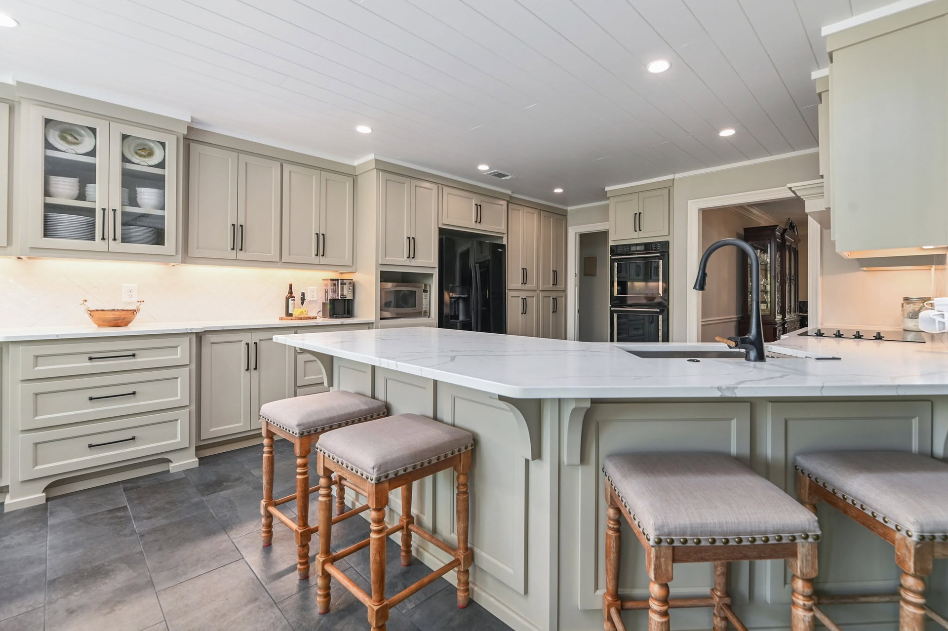 Spacious beige kitchen with island, bar stools, and stainless steel appliances