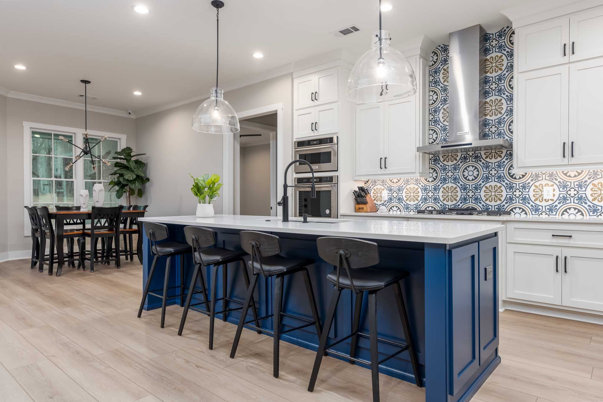Bright modern kitchen with navy island, white cabinets, pendant lights, and patterned blue tile backsplash
