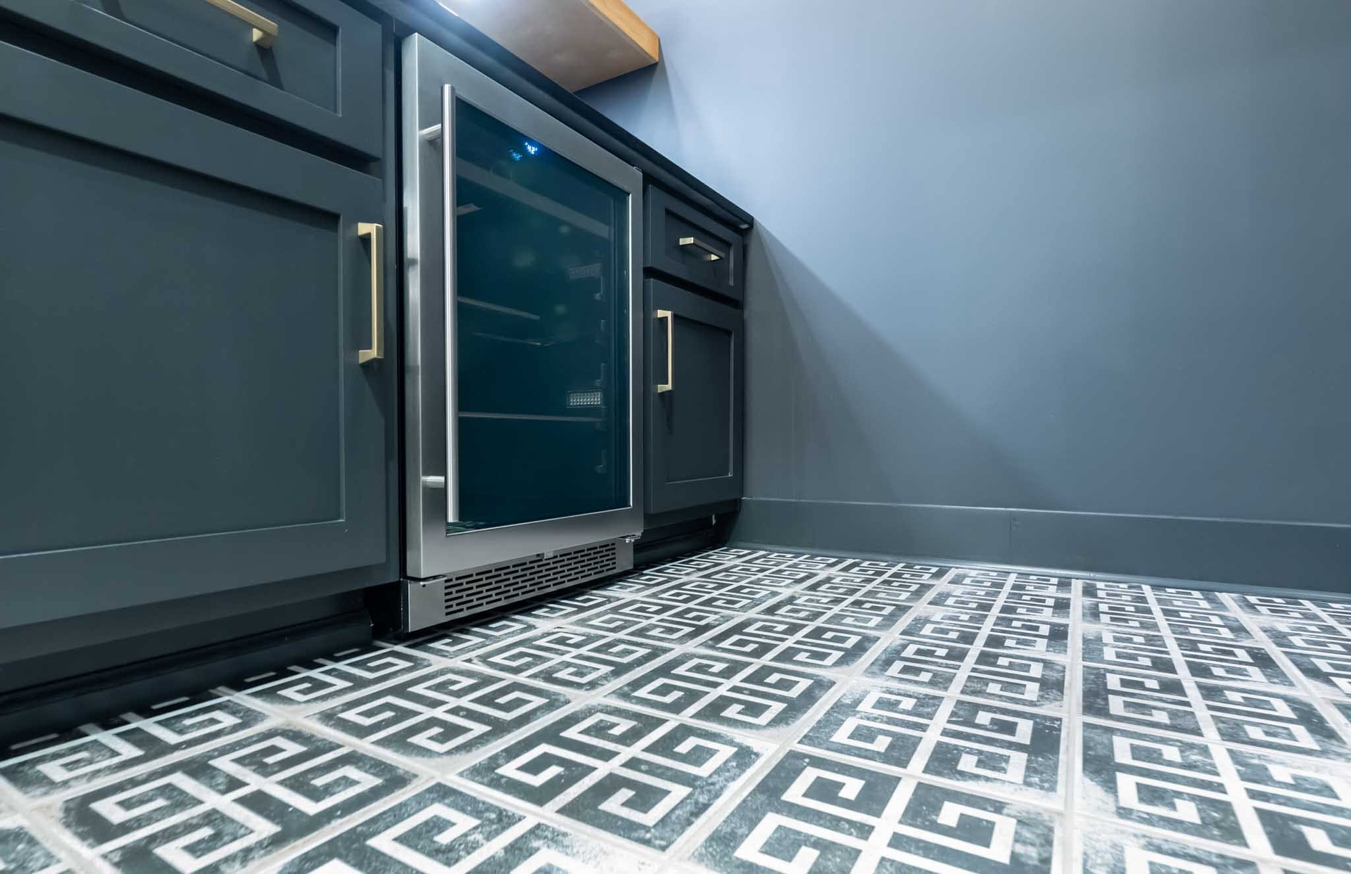 Modern kitchen floor with dark cabinets, stainless steel oven, and patterned tile flooring