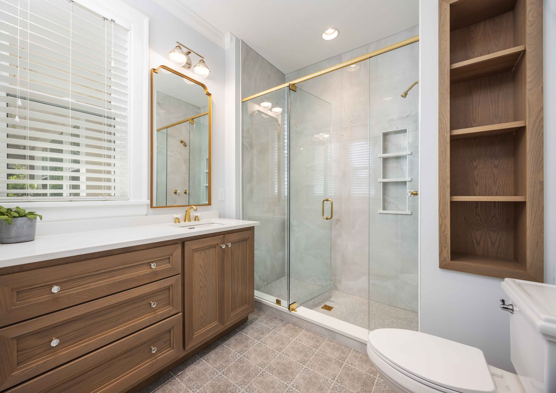 Bright modern bathroom with wood vanity, glass shower, and built-in shelving