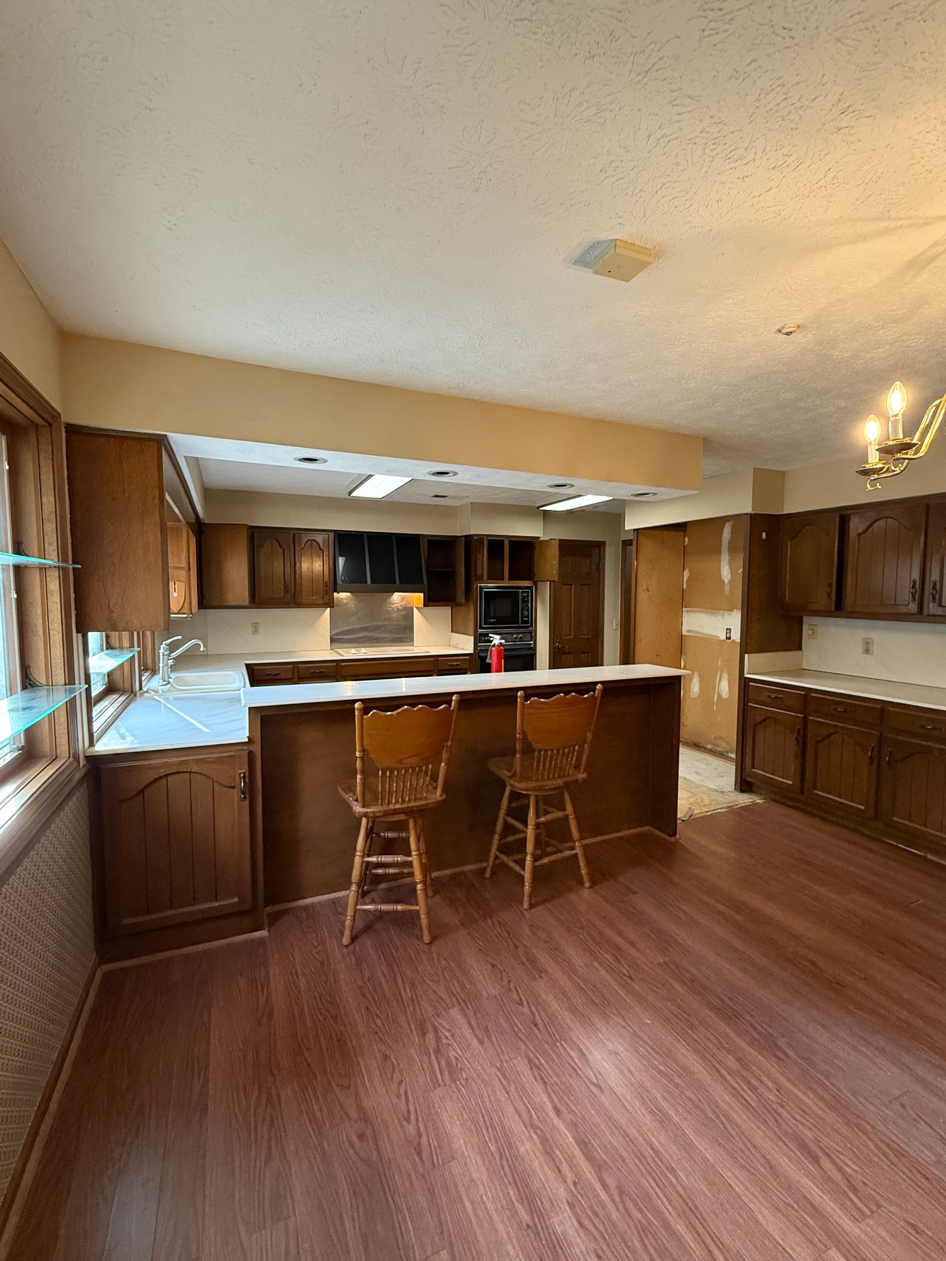 Spacious kitchen with dark wood cabinets, white island, and two stools under warm lighting.