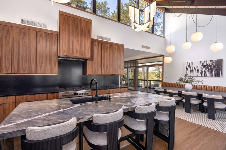 Modern kitchen and dining area with marble island, wood cabinets, pendant lights, and a large wall mural.