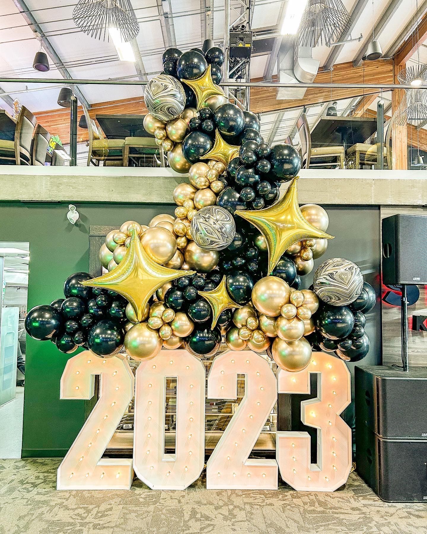 A bunch of balloons are sitting on top of a sign that says 2023.