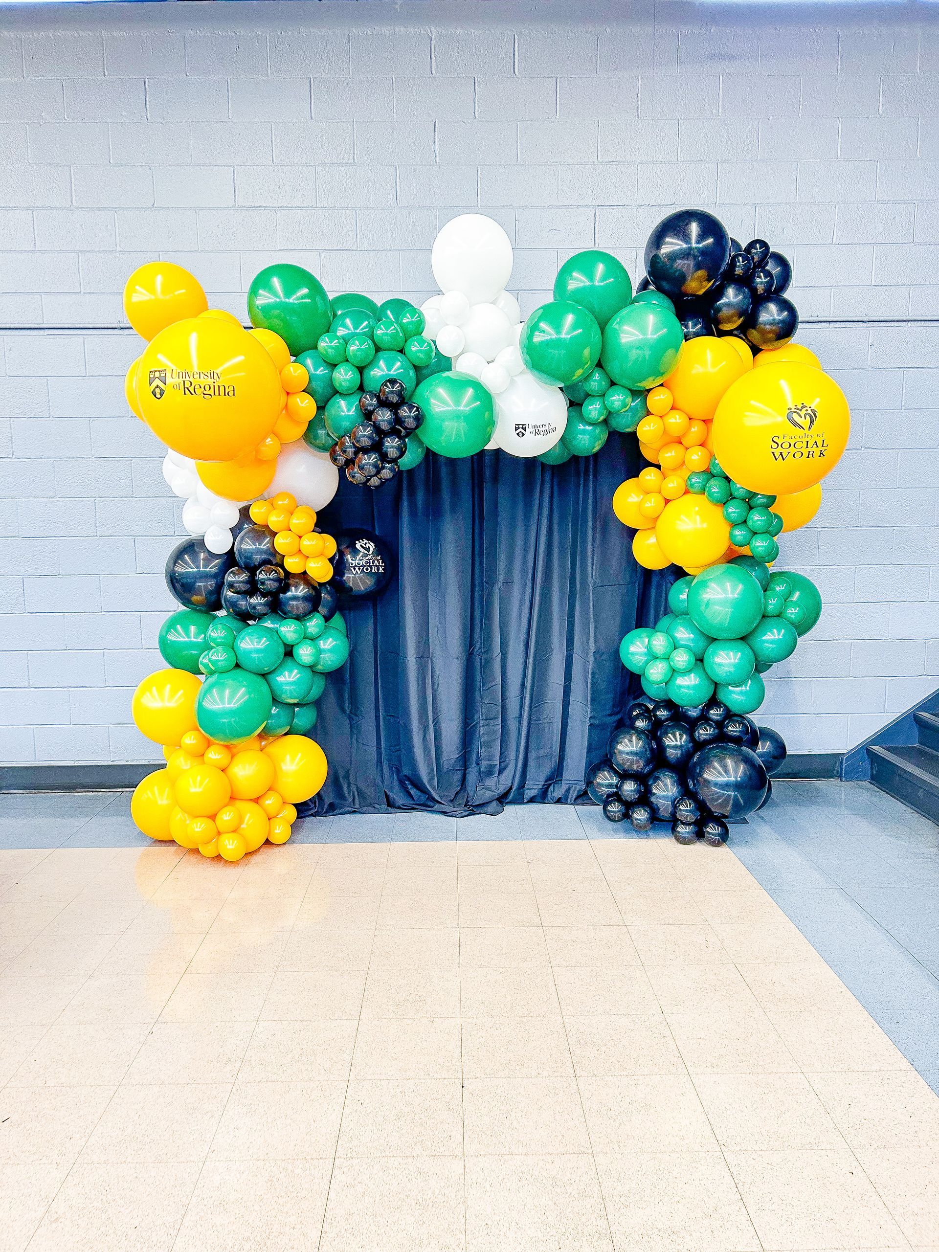 A bunch of balloons are sitting on a table in front of a brick wall.