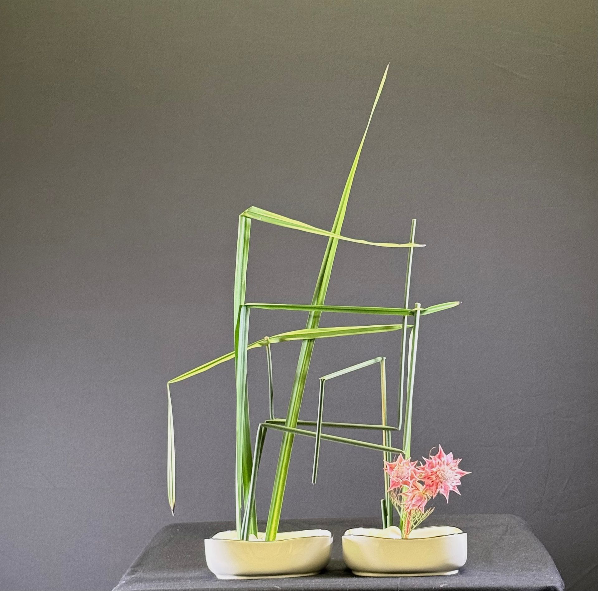 Abstracte bloemschikking met groene stelen, roze bloemen en witte vazen ​​op een zwarte achtergrond.