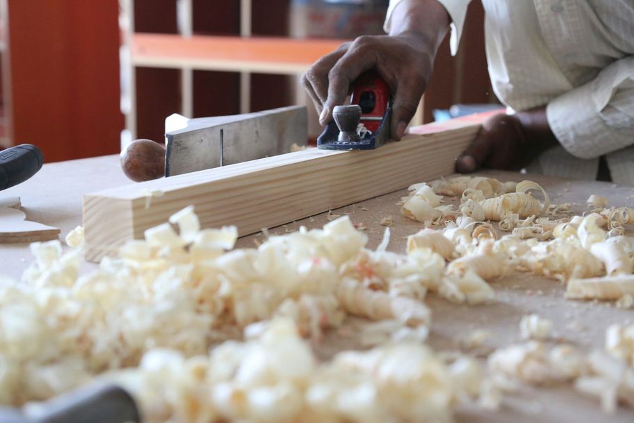 Hand planing a wooden board with curls of shavings on a workbench