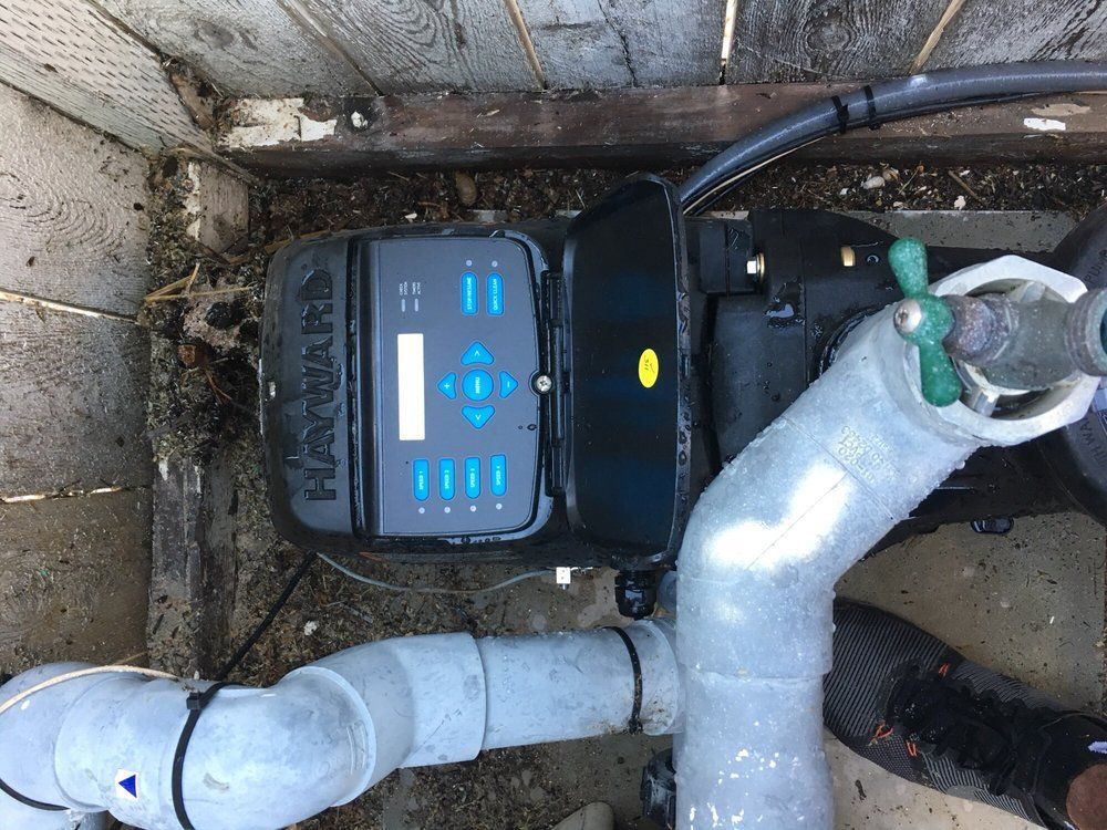 Black pump with digital display and pipes inside a concrete utility pit