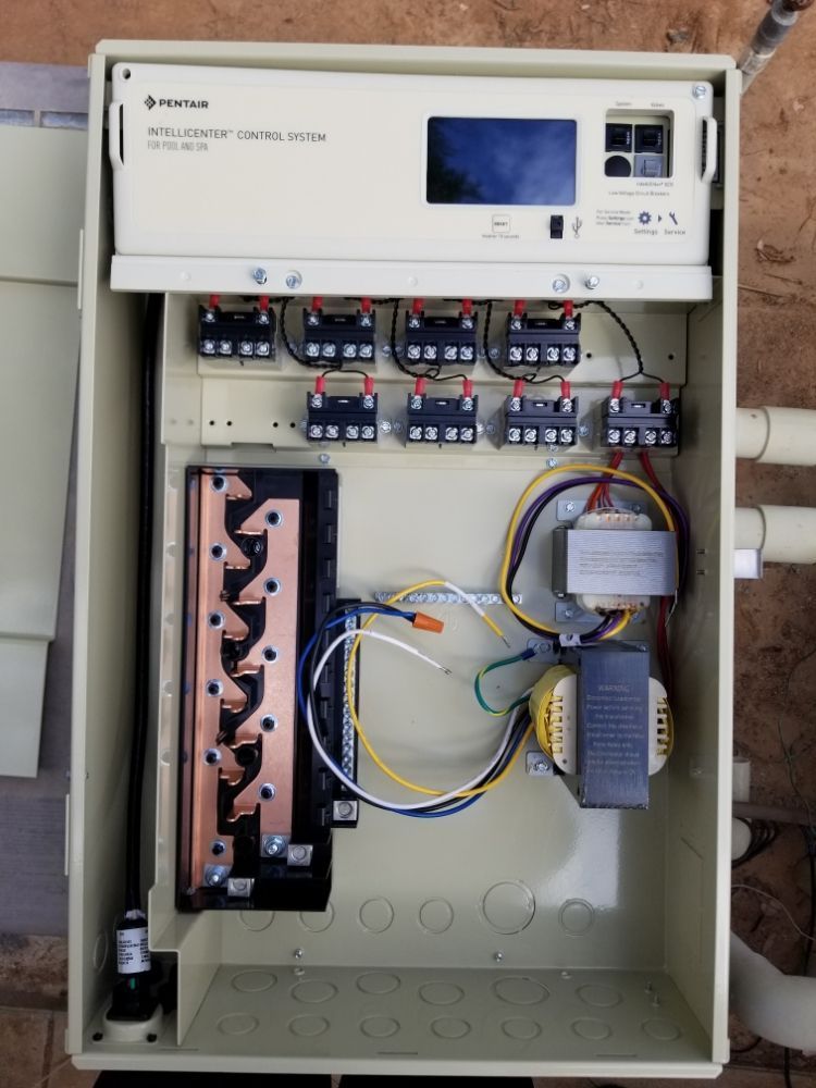 Open electrical control panel with wiring, relays, and breakers inside a beige cabinet.