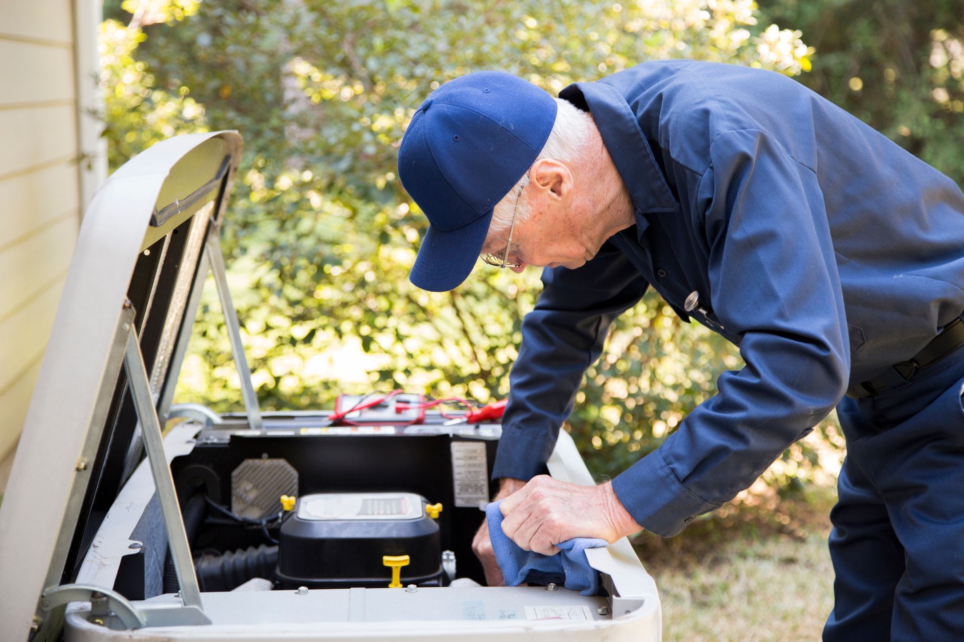 A man is working on a generator outside of a house.