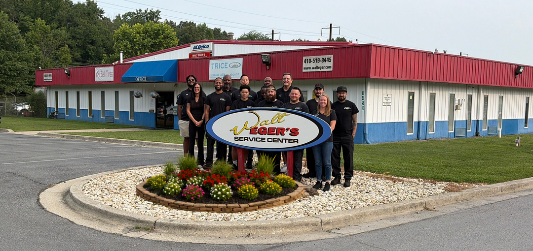 Walt Eger’s Service Center storefront with red roof, white building, and flower bed sign by the road with Walt Eger's team | Walt Eger's Service Center