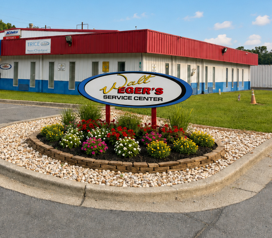 Eger’s Service Center storefront with red roof, white building, and flower bed sign by the road | Walt Eger's Service Center