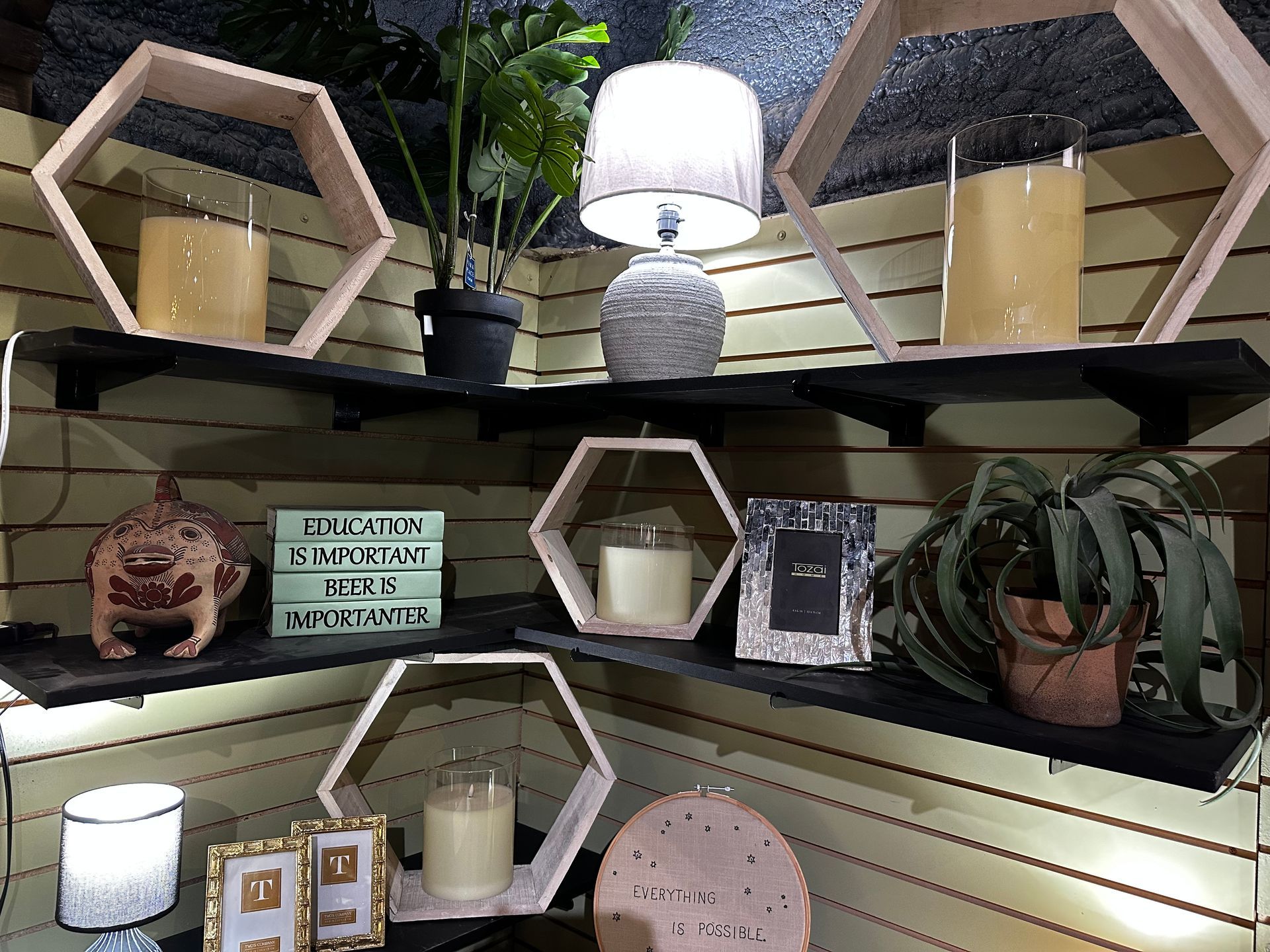 A corner of a room with shelves filled with candles and plants.