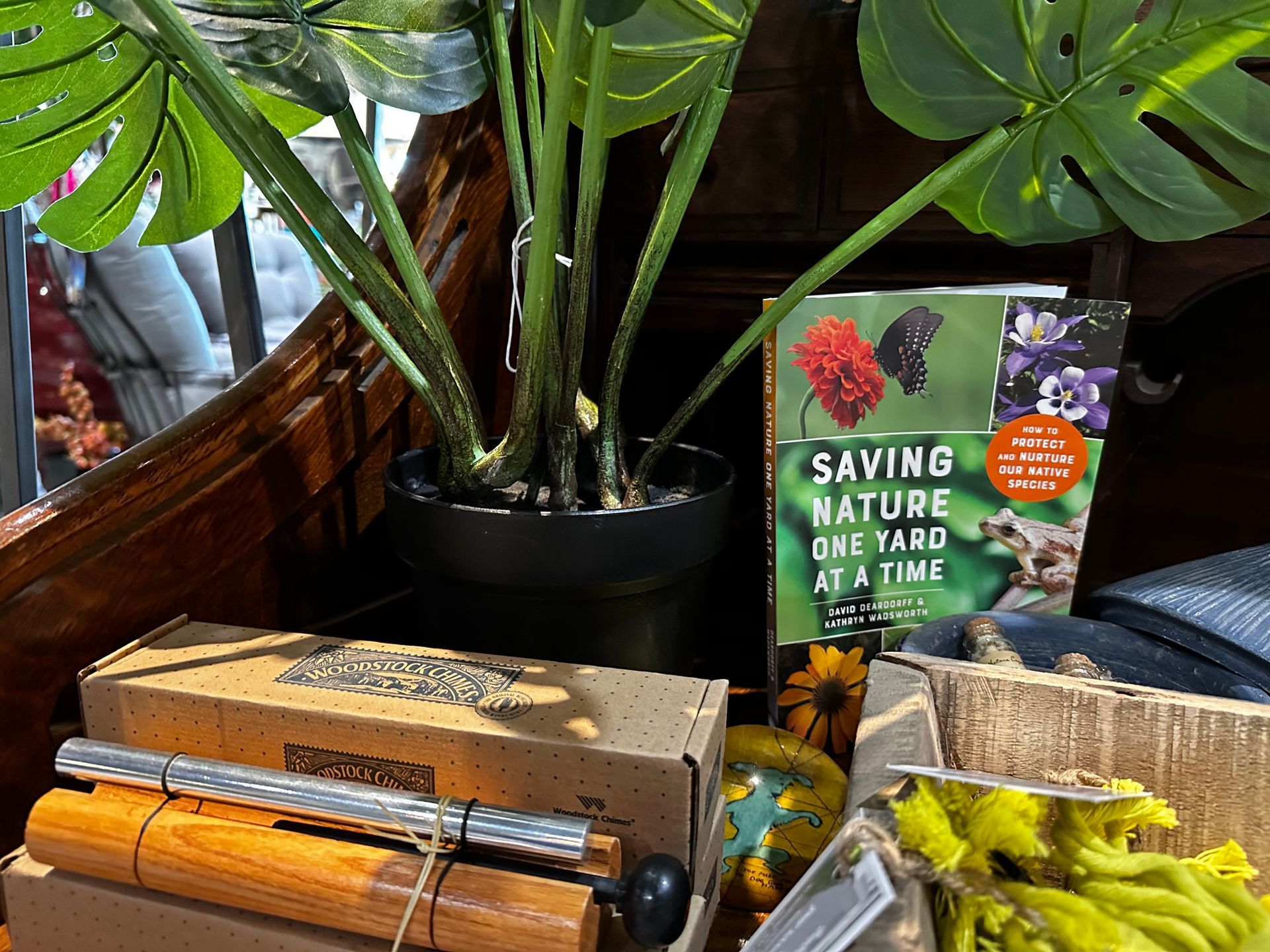 A book titled saving nature one yard at a time is sitting on a table next to a potted plant.