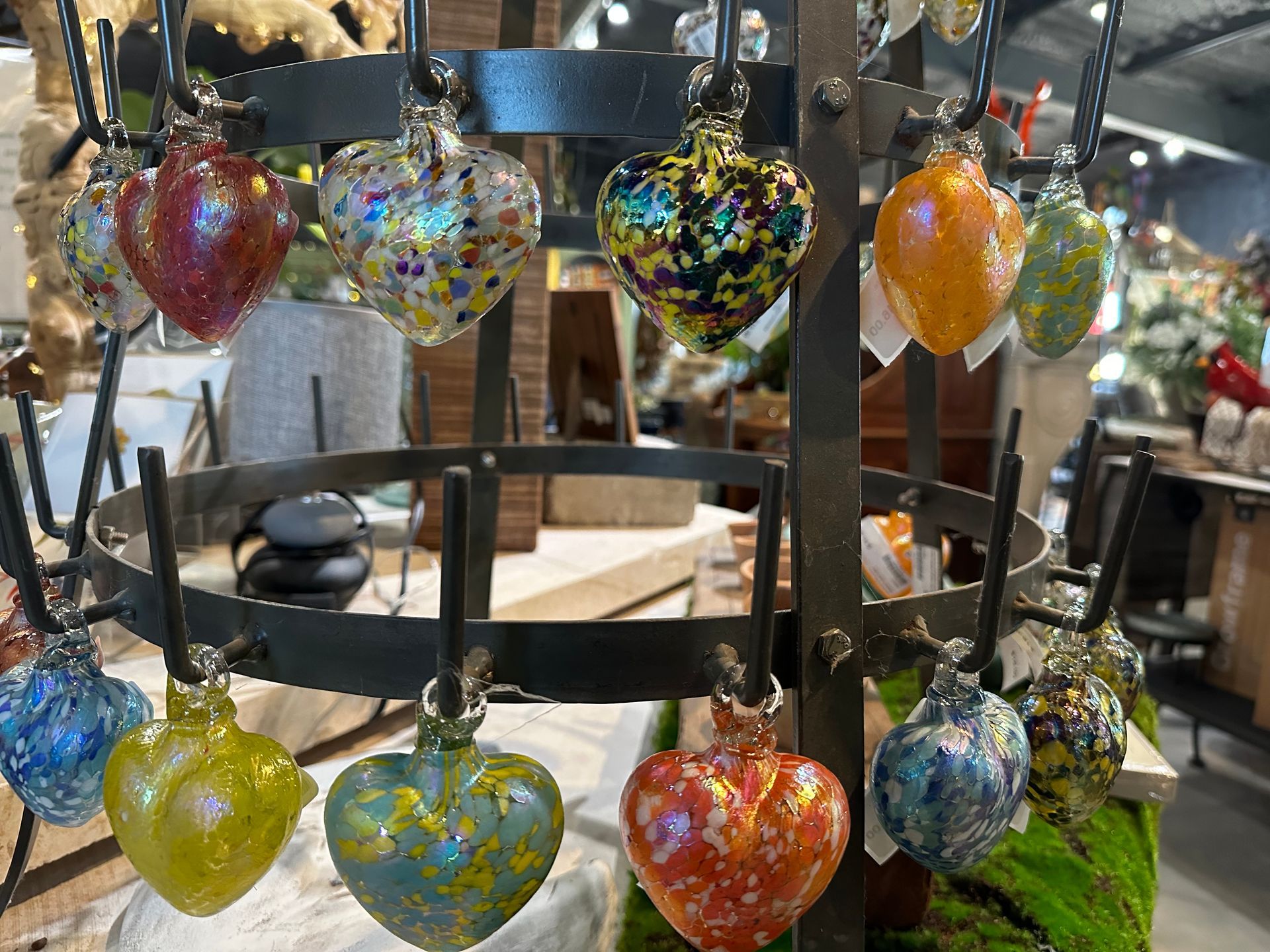 A bunch of colorful glass hearts are hanging on a rack.