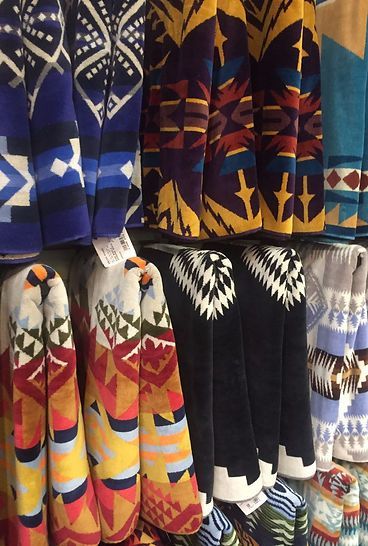 A bunch of colorful blankets are lined up on a shelf