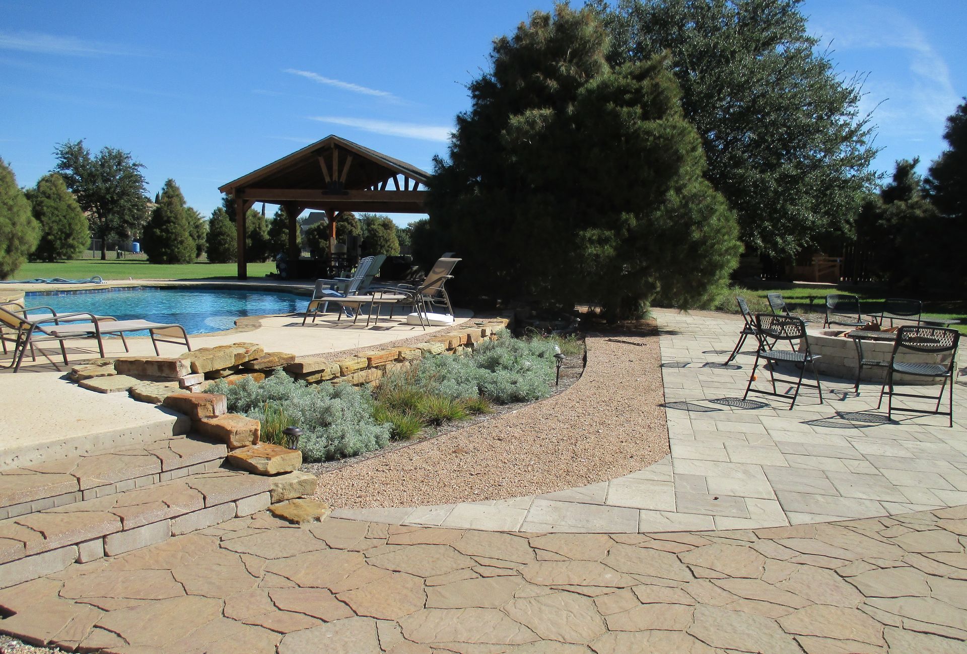 A large swimming pool with a gazebo in the background