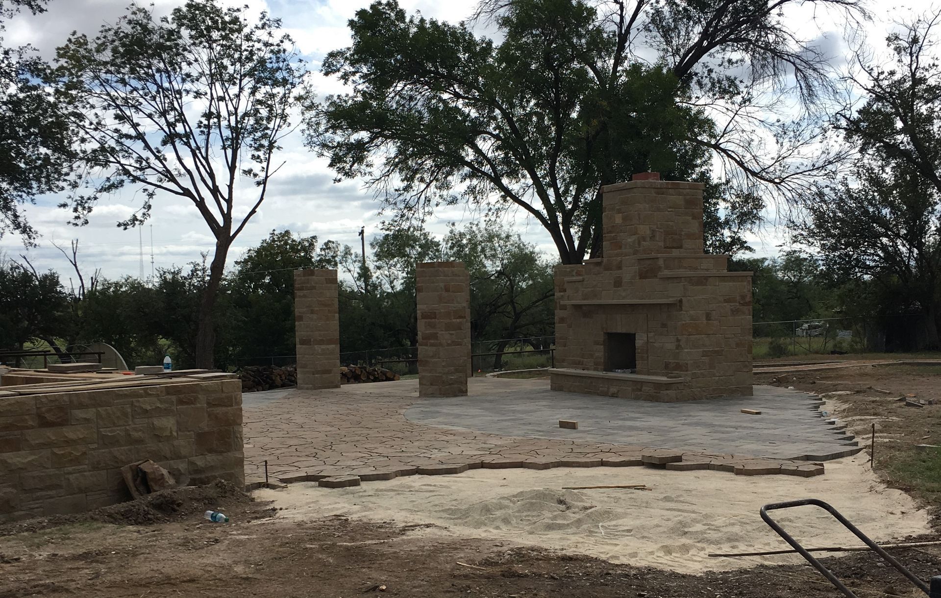 A brick fireplace is being built in the middle of a dirt field