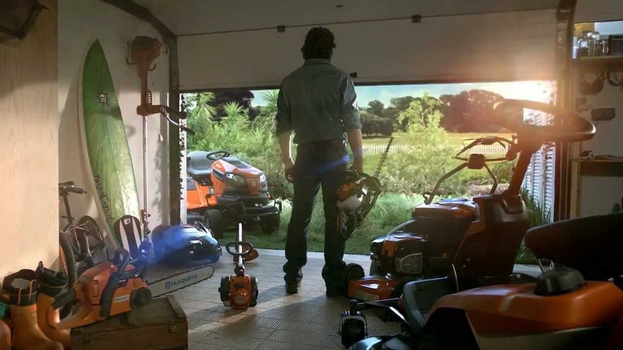 man standing in a garage full of Husqvarna tools holding Husqvarna trimmer
